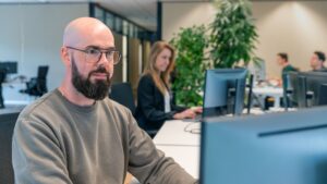Twee medewerker zittend aan hun bureau aan het werk achter een PC.