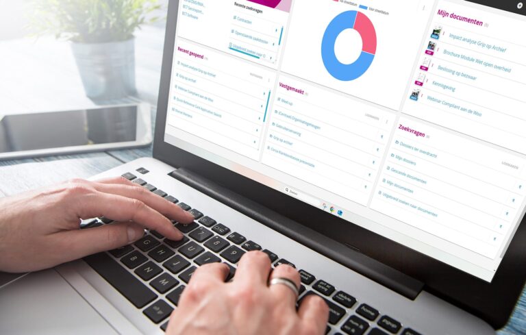 Een foto van dichtbij toont een persoon die typt op een laptoptoetsenbord. Op het scherm is een bedrijfssoftware-interface met een dashboard en een donutgrafiek zichtbaar.