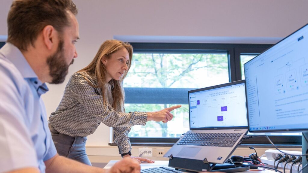 Twee medewerkers kijken naar een laptop waarvan een medewerker naar het scherm wijst