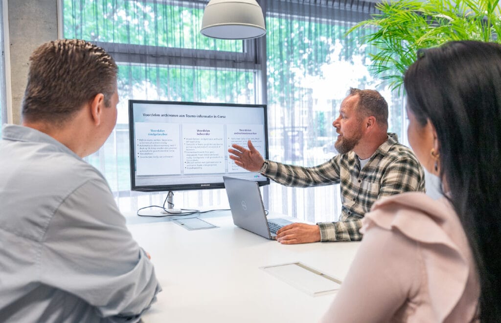 Medewerker die uitleg geeft aan twee andere collega's met een presentatie